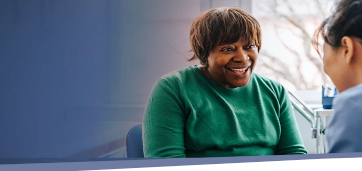 woman smiling while speaking with her healthcare provider about IMDELLTRA® treatment