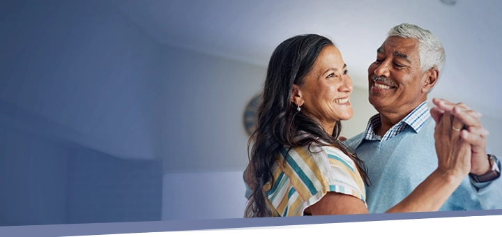 older couple smiling and dancing together indoors during IMDELLTRA® treatment  